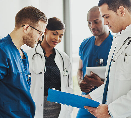 Medical-doctors-and-nurse-practitioners-discuss-paperwork-in-a-hallway